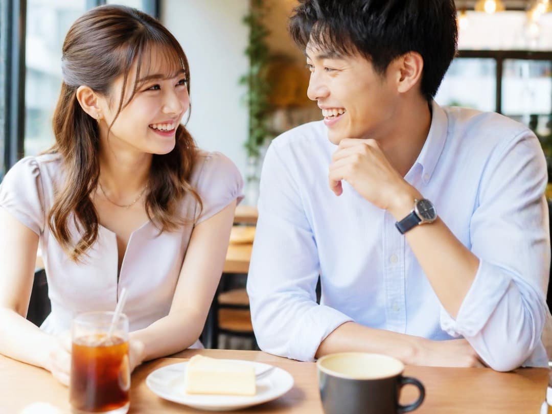 仮交際や真剣交際中のデートのイメージとしてカフェで笑顔で楽しそうに会話をする若い男女のイメージ写真
