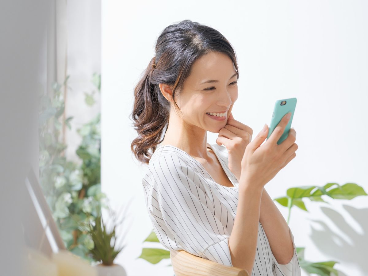 スマートフォンを手に、笑顔を見せる女性