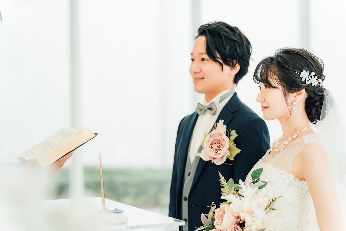 結婚式で、牧師の前に並んで立つ新郎新婦